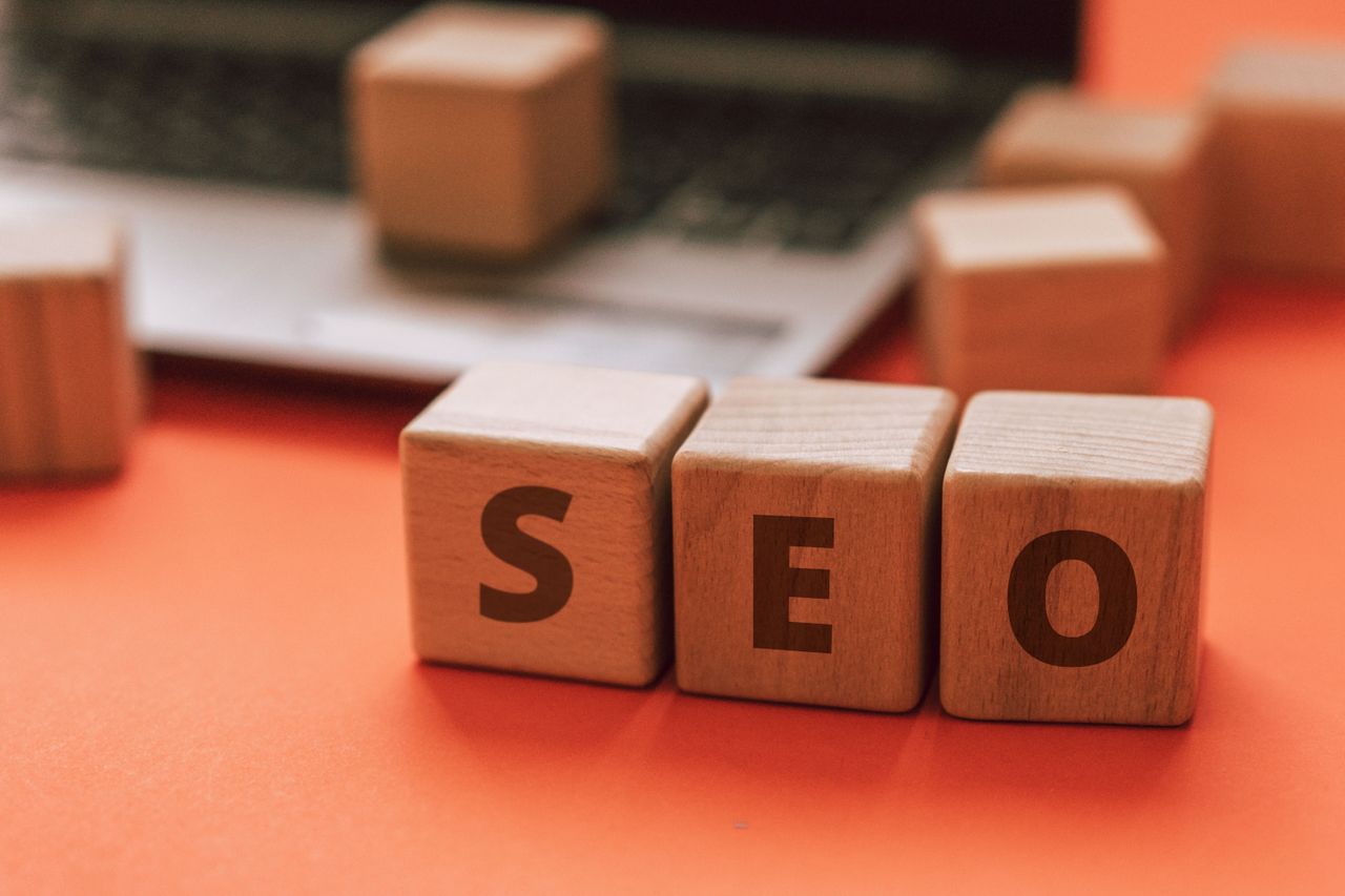 team-01 Wooden blocks spelling SEO on a laptop keyboard convey digital marketing concepts.