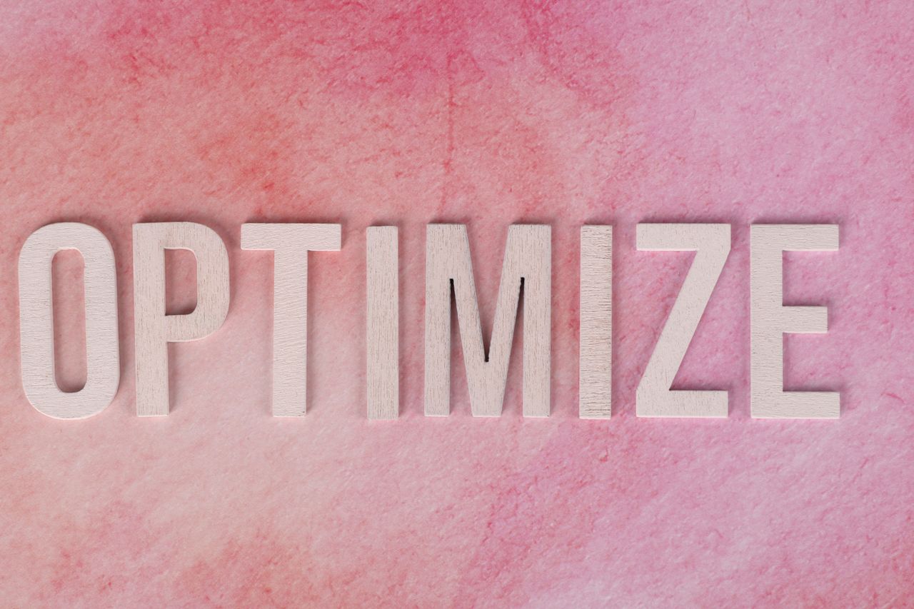 services-01 Creative display of the word OPTIMIZE on a pink textured surface.