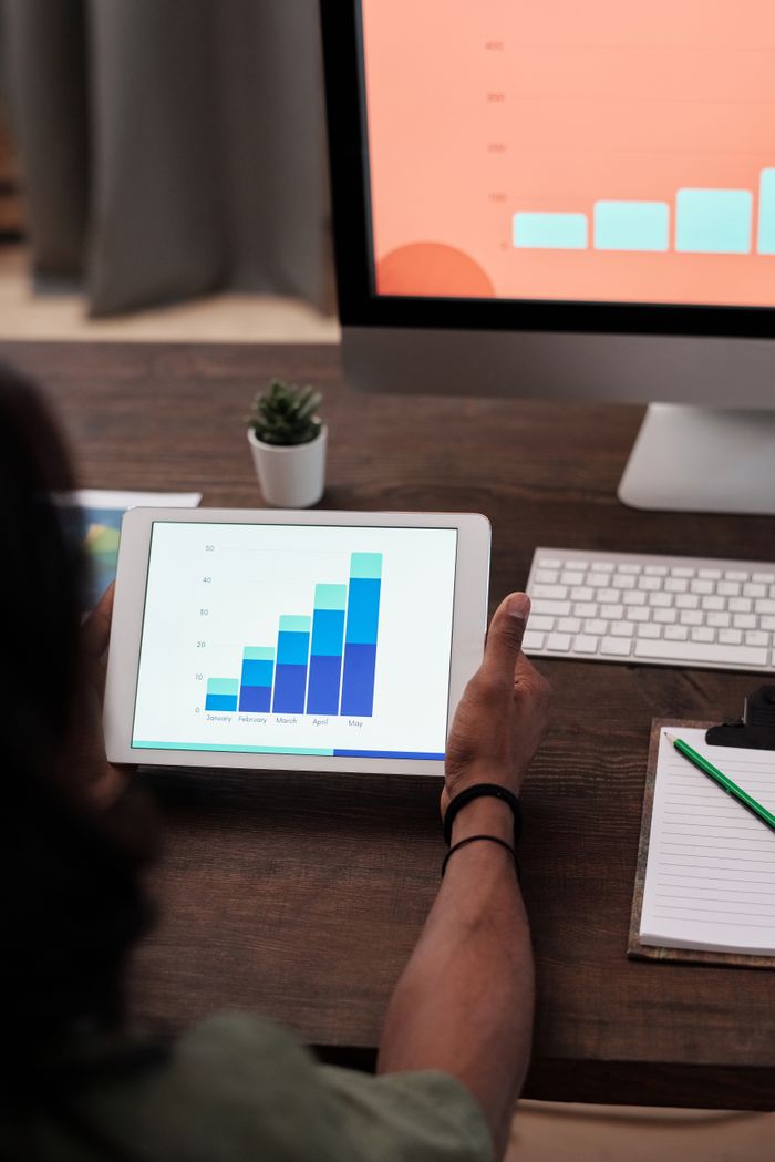 who-we-are A person reviews statistical graphs on a tablet, showcasing data analysis and technology.
